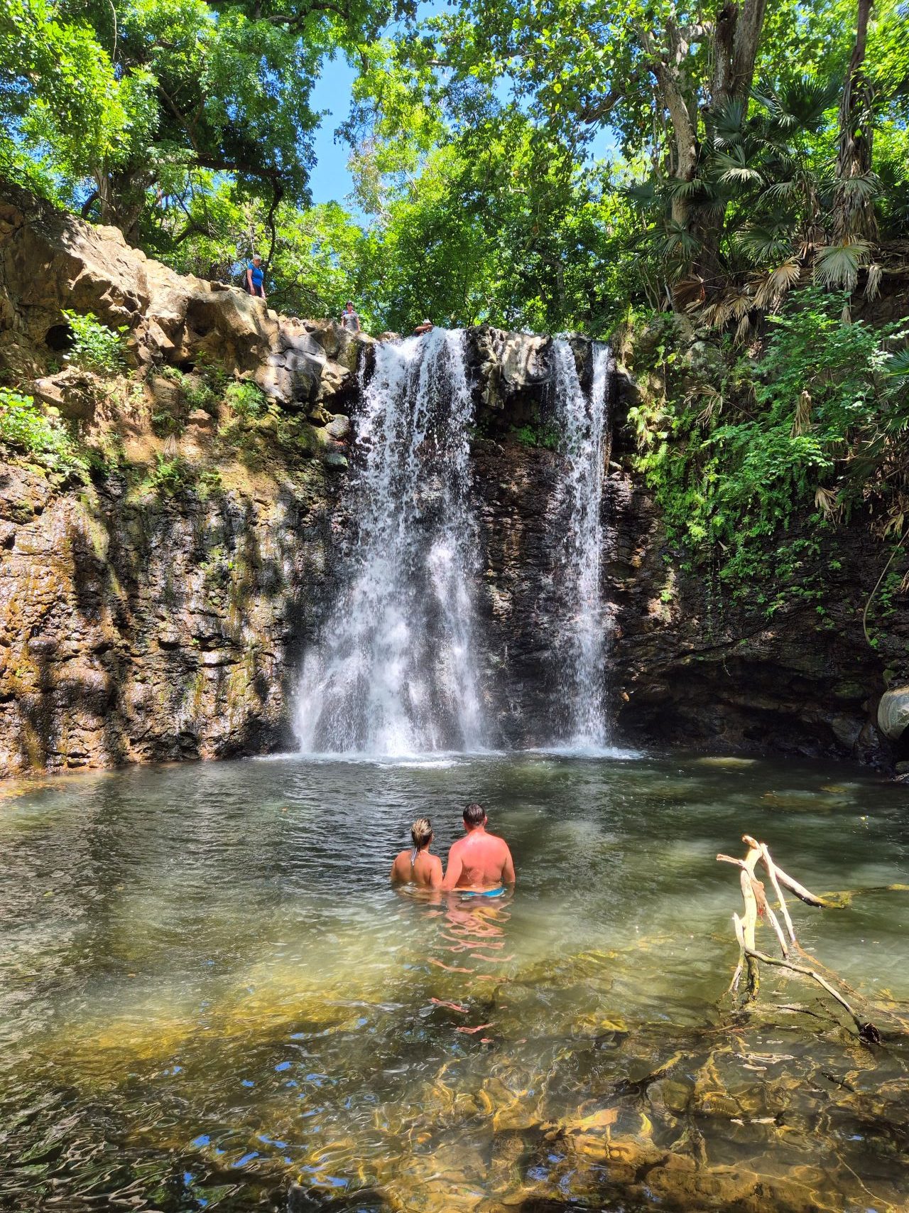"A stunning waterfall cascading down rocky cliffs in the Wild South of Mauritius, surrounded by lush greenery and vibrant trails, creating a perfect backdrop for Wild South Hiking adventures.